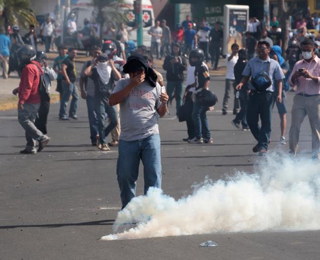 A demonstrator reacts to a tear gas canister during protests in the Nicaraguan capital Managua....