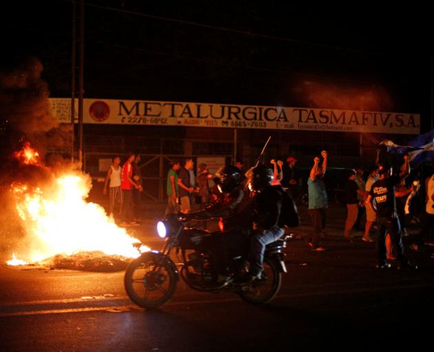 Demonstrators shout next to a burning barricade as they take part in protests in Managua,...