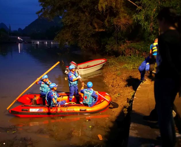 Rescue workers search for people after two dragon boats practicing to race on a river overturned,...