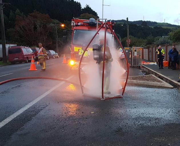 An Outram volunteer firefighter endures a cold shower on Sunday after a small spill of...