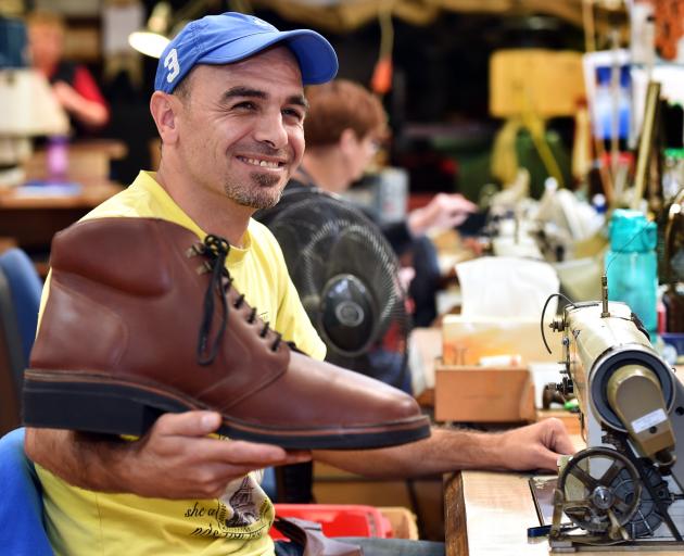 Former refugee Mohamad Ghanam holds a giant shoe at his workplace, McKinlay’s Footwear. Photo:...