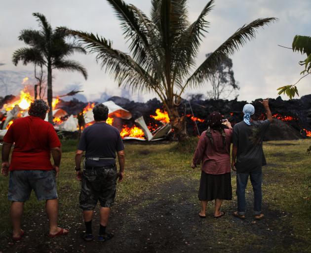 Community members watch as a home is destroyed by lava from a Kilauea volcano fissure in Leilani...