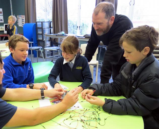 Niwa air quality scientist Gustavo Olivares, of Auckland, helps Alexandra Primary School pupils (from left) Mackai Hancock (11), Tui Simpson (10) and Victor Bond (11) assemble home heating smoke level sensors, which he designed. They are watched by fellow