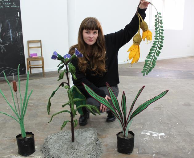 Ruth Evans displays plants she created with a range of techniques and from mostly recycled material. They are poroporo (left), harakeke and she is holding kowhai. PHOTO: ELLA STOKES