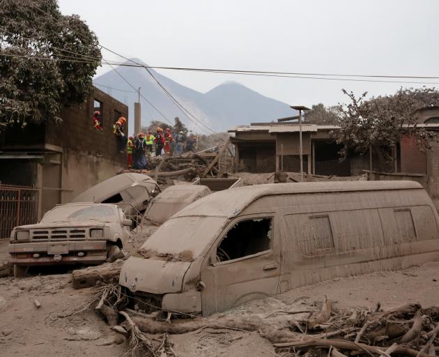 Rescue workers search the ash and mud for survivors. Photo: Reuters