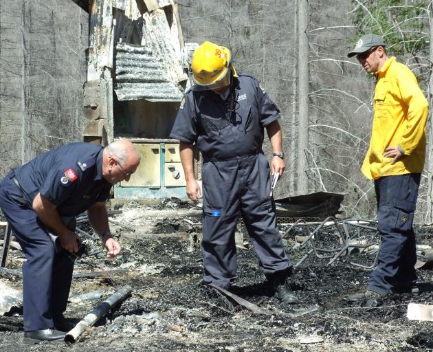 Police and firefighters inspect the scene of the Mt Aurum homestead fire at Skippers, near...