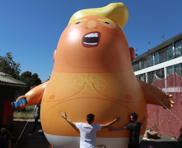 People inflate a helium filled Donald Trump blimp which they hope to deploy during The President of the United States' upcoming visit. Photo: Reuters