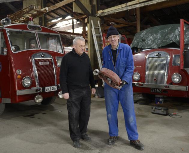 Dunedin Fire Brigade Restoration Society president Joe Hayde (left) and vice-president Gary Byford, who holds spare parts, stand beside two Dennis fire appliances built in the 1950s, one from Roxburgh and the other from Balclutha. Photos: Gerard O'Brien