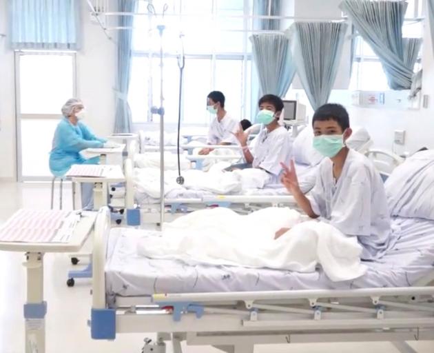 A screen grab shows boys rescued from the Thai cave wearing mask and resting in a hospital in...