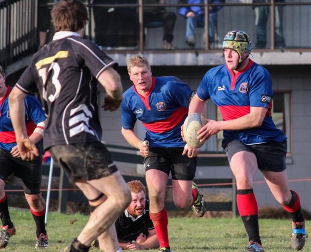 Owaka player Reuben Crossan takes the ball up with support from Chris Chittock (centre left) and...