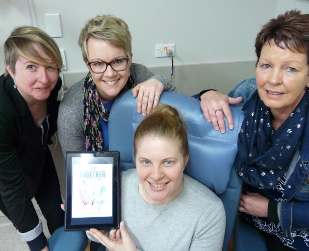 Demonstrating one of three new tablets, loaded with new cancer survivor magazine In It Together,...