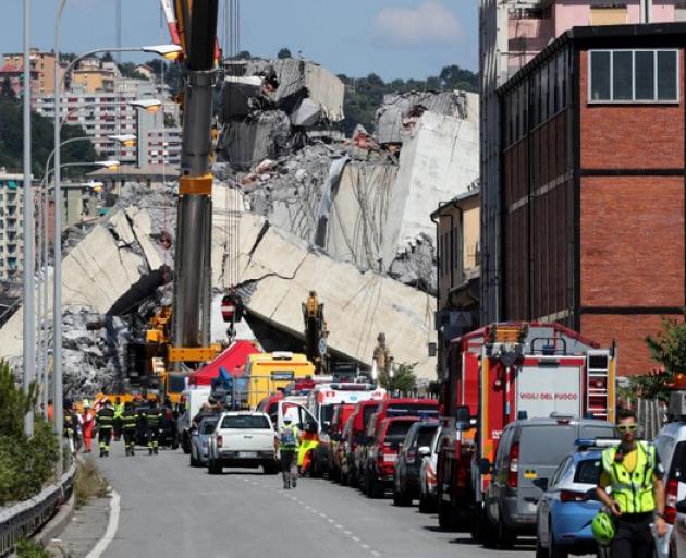 Firefighters and rescue workers stand at the site of a collapsed Morandi Bridge. Photo: Reuters