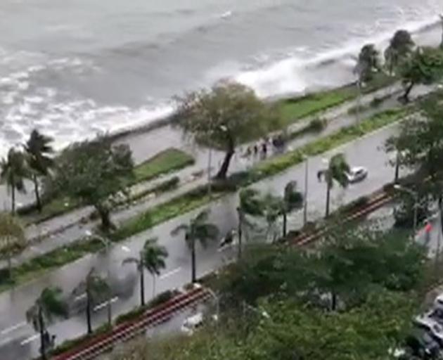 Vehicles move through flooded roads as strong winds blow at Roxas Boulevard in Manila. Photo:...