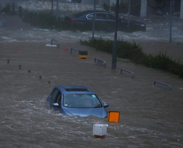 A car is stranded in seawater as high waves hit the shore at Heng Fa Chuen, a residental district...