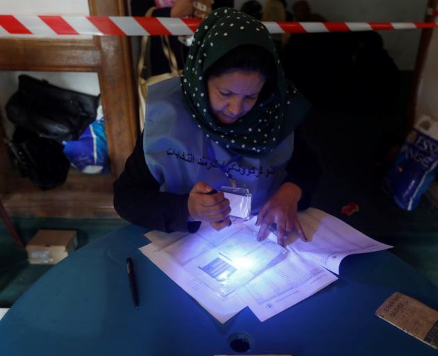 An election official checks voter's documents with an UV flashlight at a polling station during a...