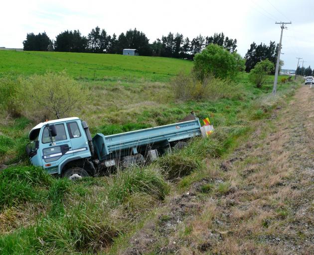 A gravel truck rests in swampy ground off the Owaka Highway near Finegand yesterday. It left the road at low speed after its occupant apparently fainted. Photo: Richard Davison
