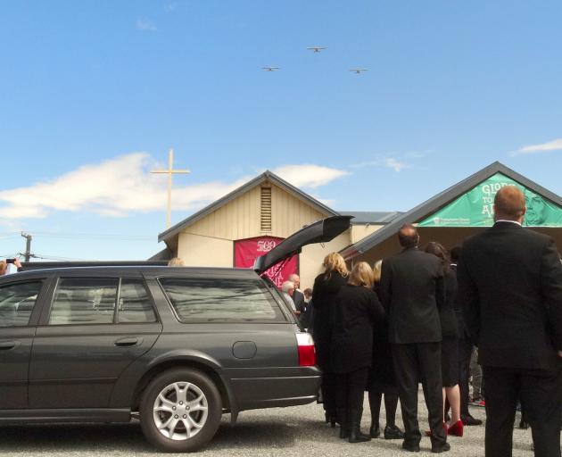 Mourners watch a fly-past of Glenorchy Air planes after the funeral of the company's co-founder,...