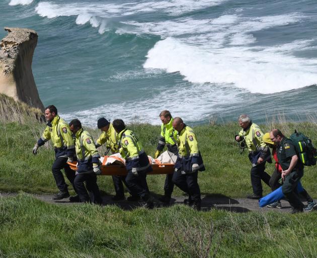 Firefighters carry German tourist Johanna Langner (25) up the steep access track at Tunnel Beach...