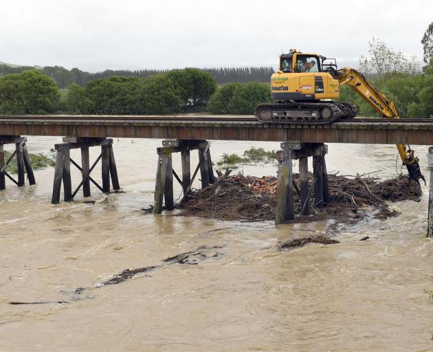 A digger clears debris from a rail bridge on the Shag River north of Palmerston. Photo: Stephen Jaquiery