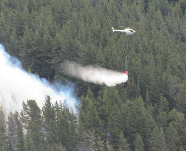 A helicopter with a monsoon bucket fights a fire at a hillside in Hawea. Photo: Mark Price