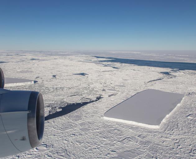 A sharp-angled, tabular iceberg floats among sea ice just off of the Larsen C ice shelf in the...