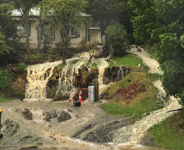 Water gushes down the hill in front of a Ravensbourne house yesterday. Photo: Gregor Richardson