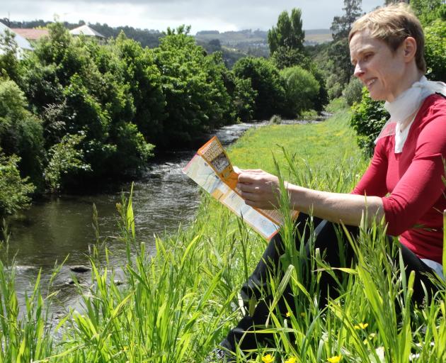 Dunedin Botanic Garden information services officer Clare Fraser sits beside the Water of Leith reading the new Dunedin Volcano Trail brochure, which highlights the many volcanic features in the garden. Photo: Brenda Harwood