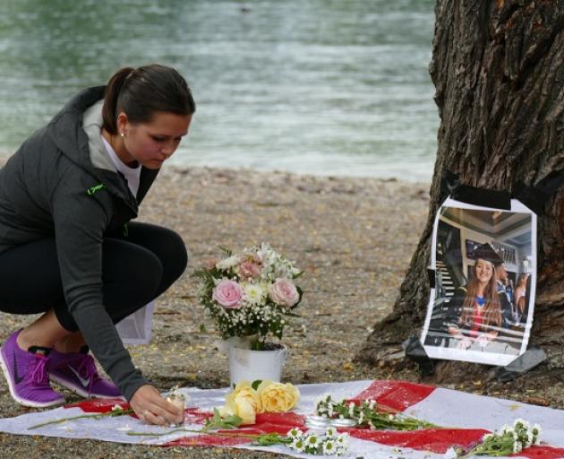 Katie Stafford places a candle at the memorial for Grace Millane in Queenstown. Photo: Mountain Scene