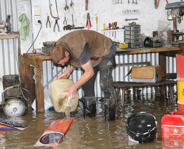 Otago Airspread pilot James Allan pitches in to help clear floodwater at the company’s hangar at...