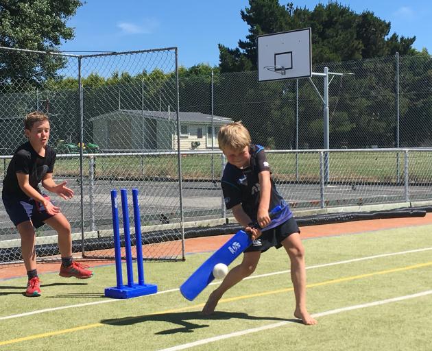 Unleashing a cover drive during the OCCA holiday programme  at Maniototo Area School is Angus McDiarmid (10) as Charlie Falconer (9) keeps wicket. Photo: Adam Burns