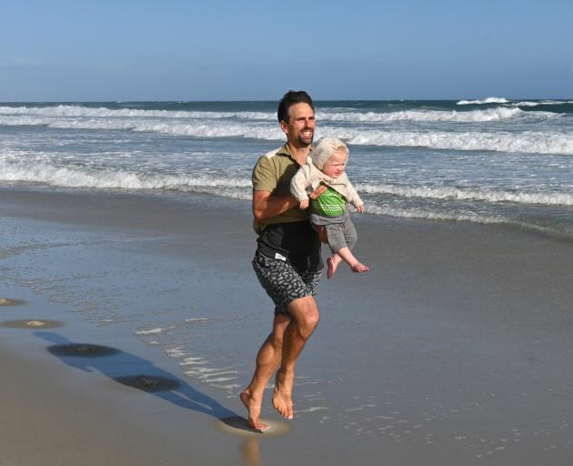 Matthew Onarheim-Smith runs along St Kilda Beach carrying his 14-month-old son Gabriel. Photo: Linda Robertson