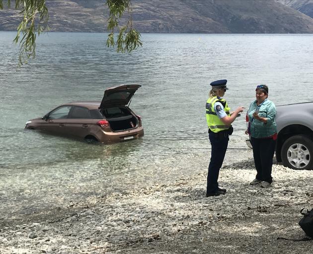 An American tourist talks to police after her rental car rolled into Lake Wakatipu yesterday. Photo: Daisy Hudson