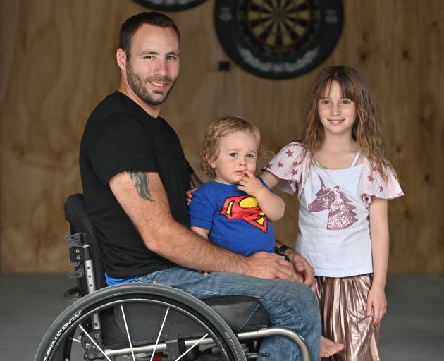 Disabled darts player Rob Gillan with children Connor (18 months) and Bailey (7) in his garage...