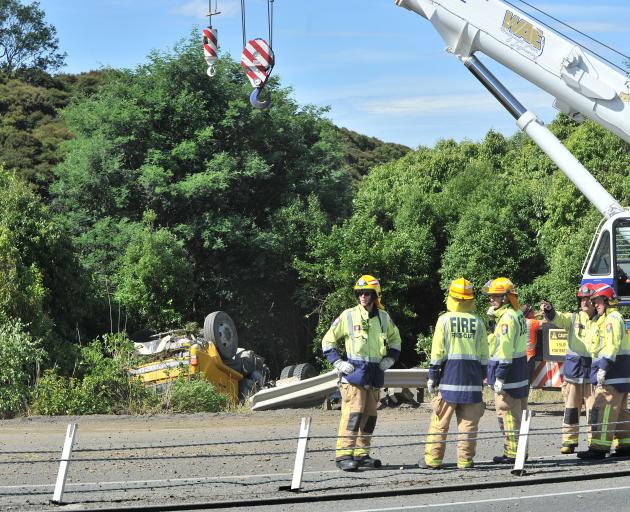A crane prepares to retrieve a gravel truck from the side of the Southern Motorway after it rolled near Saddle Hill yesterday. Photo: Christine O'Connor