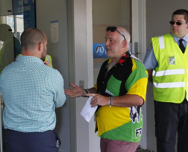 Riverton resident Wayne Hill (centre) speaks to an unknown bank member about the closure of the last bank in Riverton as a security guard looks on. Photo: Giordano Stolley