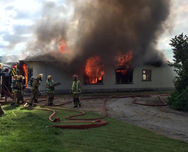 Fire crews work to control the fire raging though a four-bedroom homestead on Tokarahi-Tapui Rd...