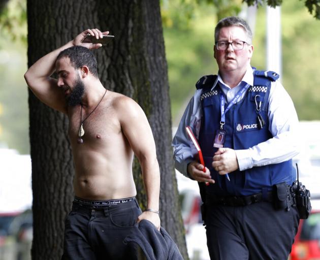 A police officer escorts a man away from a mosque in central Christchurch. Photo: AP