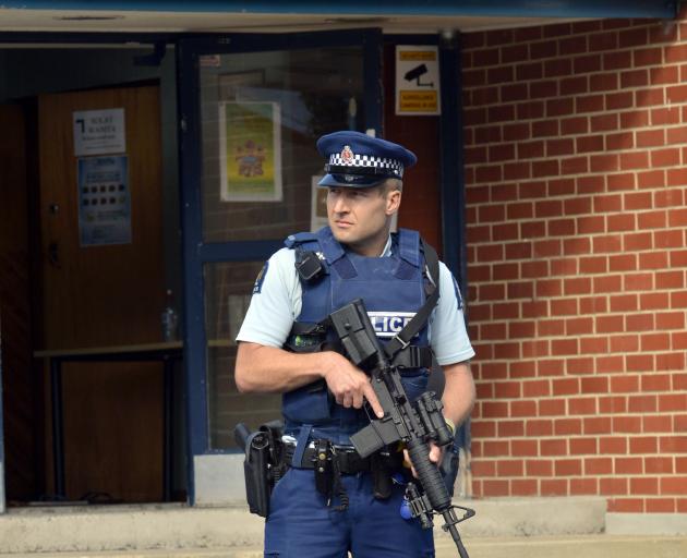 An armed police officer guards the Al Huda Mosque in Dunedin this afternoon following the...