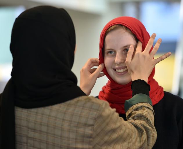 Shahad Alismaily puts a hijab on fellow student Maggie Wilson (19) at the University of Otago....