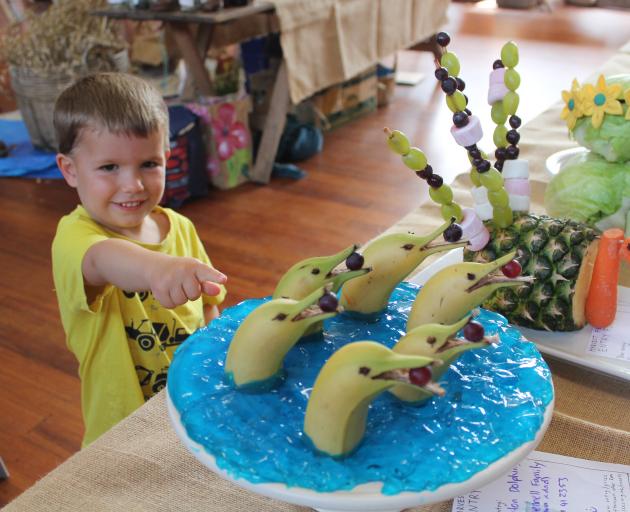 Denver Lush points to a dolphin fruit sculpture made with bananas, grapes and jelly during the...