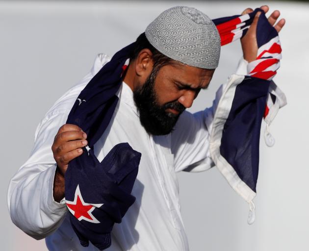 A man carries a New Zealand flag during a burial ceremony for victims of the mosque attacks in...