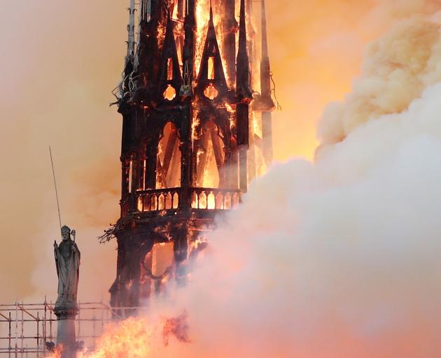 Smoke billows as fire engulfs the spire before it collapsed. Photo: Reuters