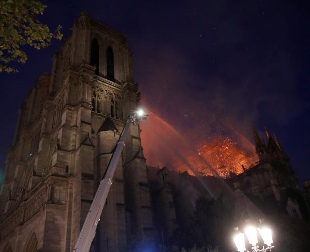 Paris Fire brigade members spray water to extinguish flames as the Notre Dame Cathedral burns in...