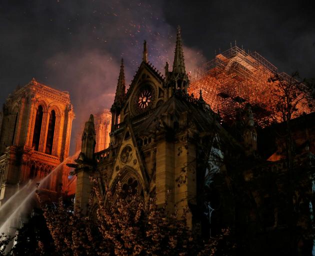 Sparks fill the air as Paris Fire brigade members spray water to extinguish flames as the Notre Dame Cathedral burns in Paris. Photo: Reuters