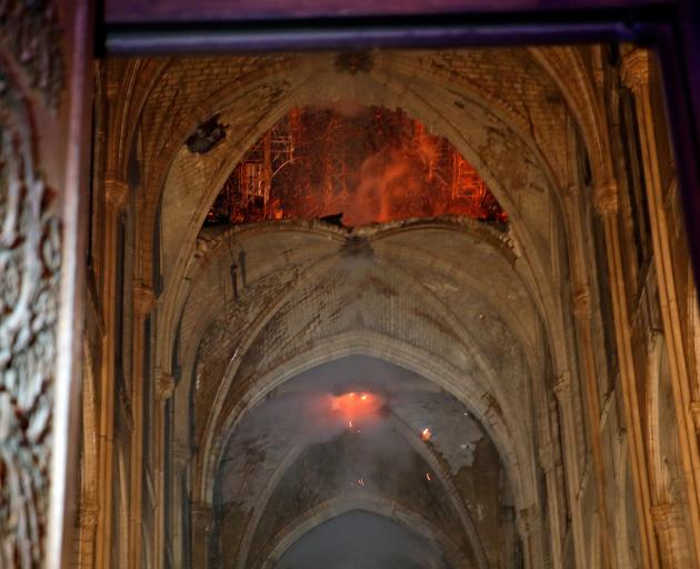 Flames and smoke are seen as the interior continues to burn inside the Notre Dame Cathedral in...