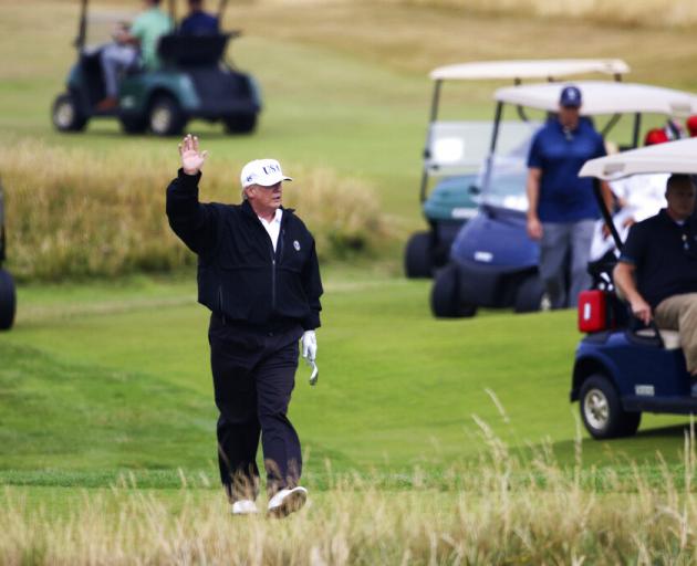 In this July 14, 2018 file photo, President Donald Trump waves to protesters while playing golf...