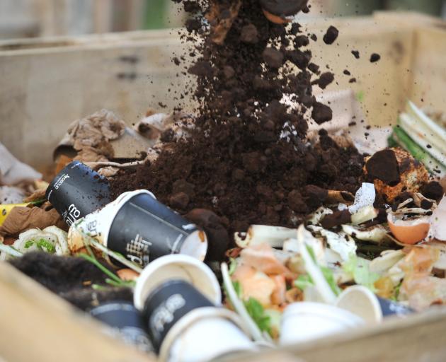 Coffee grounds, compostable coffee cups and food scraps are poured into one of Doubt Not's...