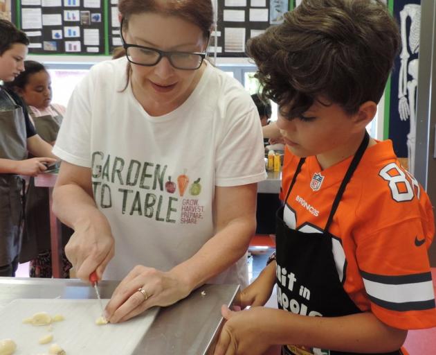 Linda Taylor shows Jack Brosta (9) how to slice garlic. 