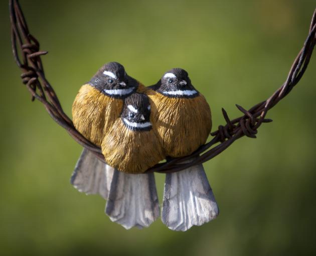 Baby fantails carved from kauri huddle on barbed wire. PHOTO: ERIC SCHUSSER
