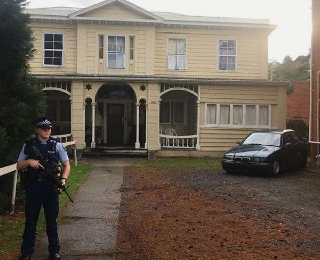 An armed police officer stands guard at the scene of an apparent drive-by shooting at a boarding house in Great King St. Photo: George Block